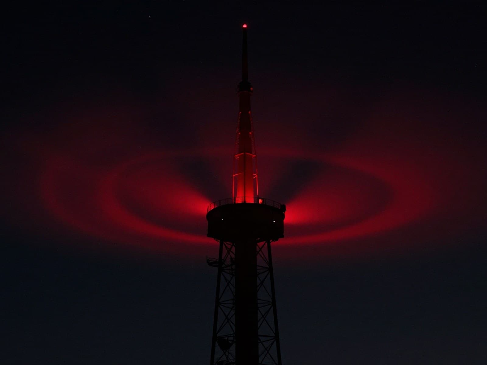 Cinematic broadcast tower silhouette against a night sky with a pulsing red signal glow